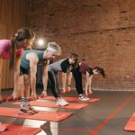 Fitness group performing exercises with dumbbells in a modern yoga studio setting.